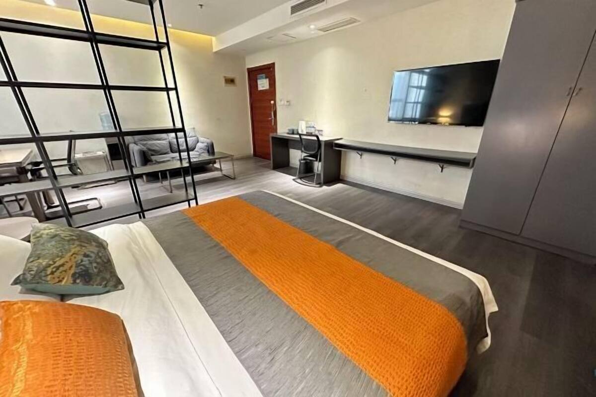 A hotel room with a bed, a desk, a chair, a TV, and a wardrobe.