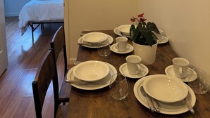 Een eethoek met een tafel voor vier personen, een bloempot en een schilderij aan de muur.