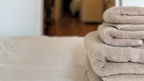 Een net opgemaakt bed met een stapel opgevouwen handdoeken.