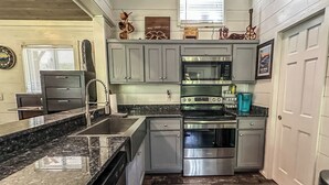 A kitchen with grey cabinets, a stainless steel stove, and a microwave. - Cozy hot tub cabin in charming Scaly Mountain, what a gem! (Scaly Mountain)
