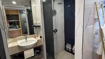 Un baño moderno con lavamanos, espejo y ducha.