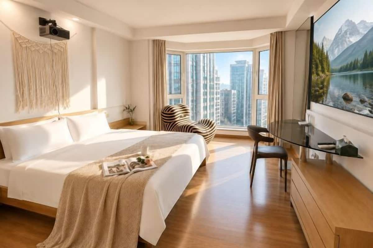 Une chambre d’hôtel avec un grand lit, un bureau, une chaise, une télévision et une fenêtre donnant sur la montagne.