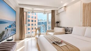 Ein Hotelzimmer mit Bett, Fernseher, Balkon und Stadtblick.