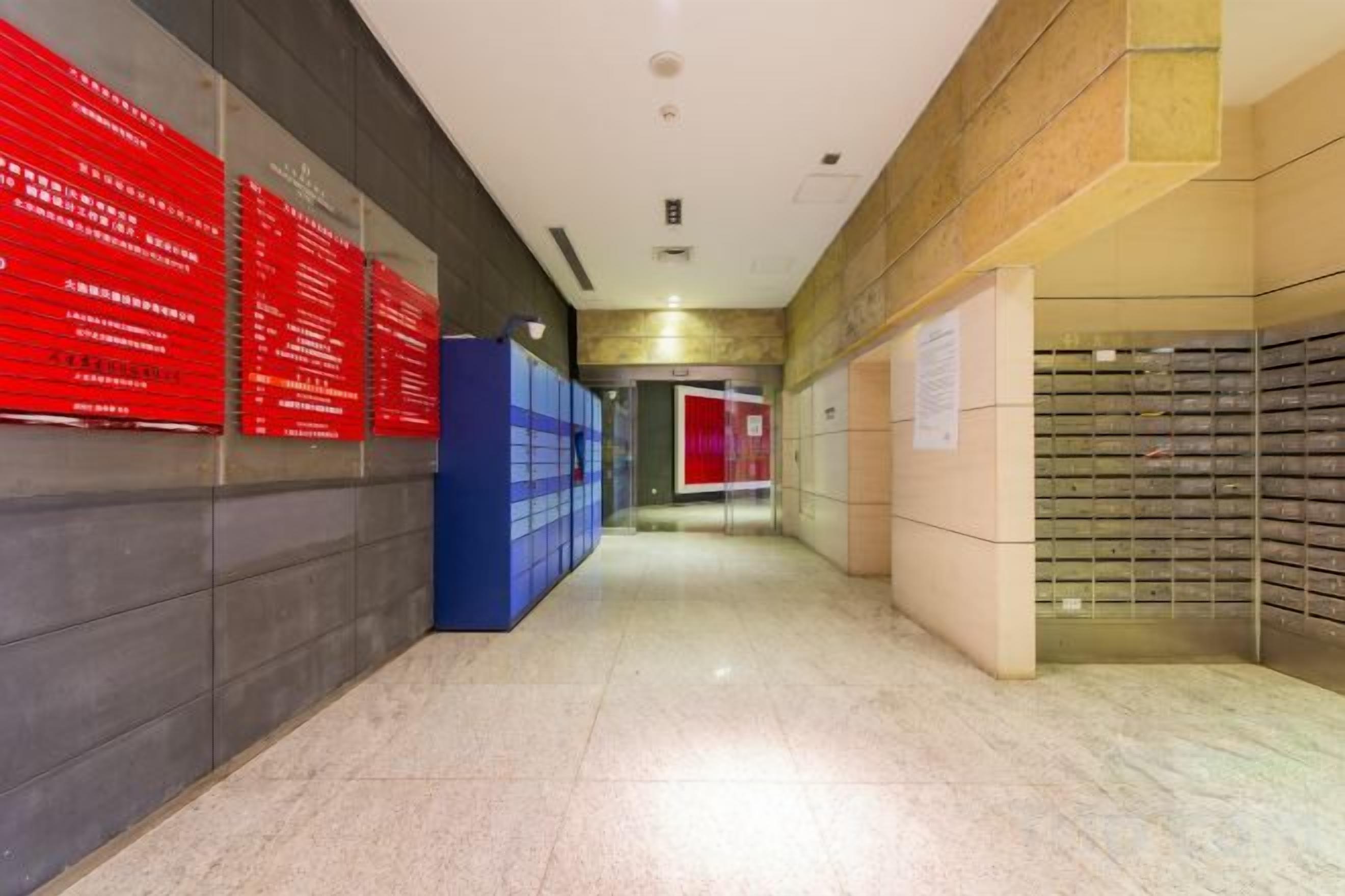 A hallway with lockers, red informational signs, and a red door at the end.