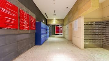 A hallway with lockers, red informational signs, and a red door at the end.