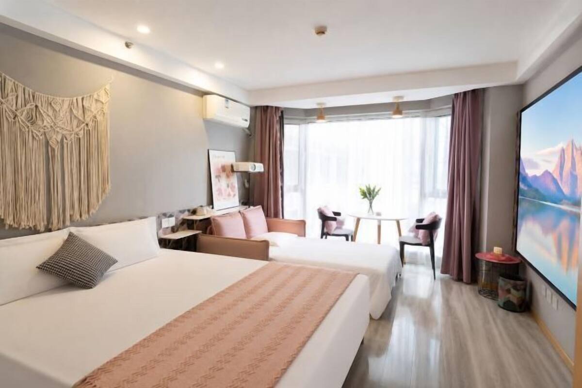 Une chambre d’hôtel avec deux lits, un bureau, une chaise, une télévision et une grande fenêtre.