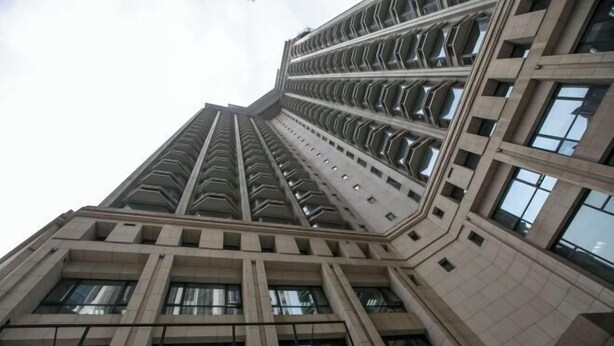 Un edificio de gran altura con un diseño arquitectónico moderno, que presenta una cuadrícula de ventanas y una fachada geométrica.