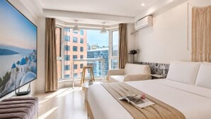 A hotel room with a large bed, a TV, a balcony with a view of buildings, and a cityscape. - Love Holiday Hotel (Dalian Zhongshan Square Railway Station) (Dalian)