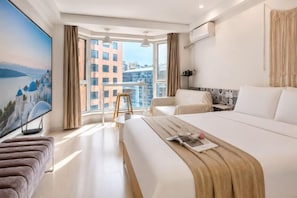 A hotel room with a large bed, a TV, a balcony with a view of buildings, and a cityscape. - Love Holiday Hotel (Dalian Zhongshan Square Railway Station) (Dalian)