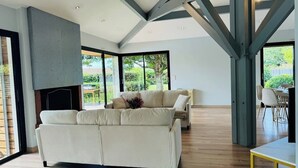 A spacious living room with a large sofa, a dining area, and a fireplace.