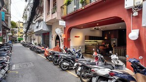 Een rij geparkeerde scooters voor een gebouw met een rode gevel en een bord waarop een restaurant aangegeven staat.