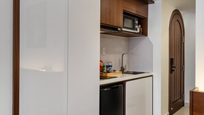 Een kleine keuken met witte kastjes, een magnetron en een vaatwasser.