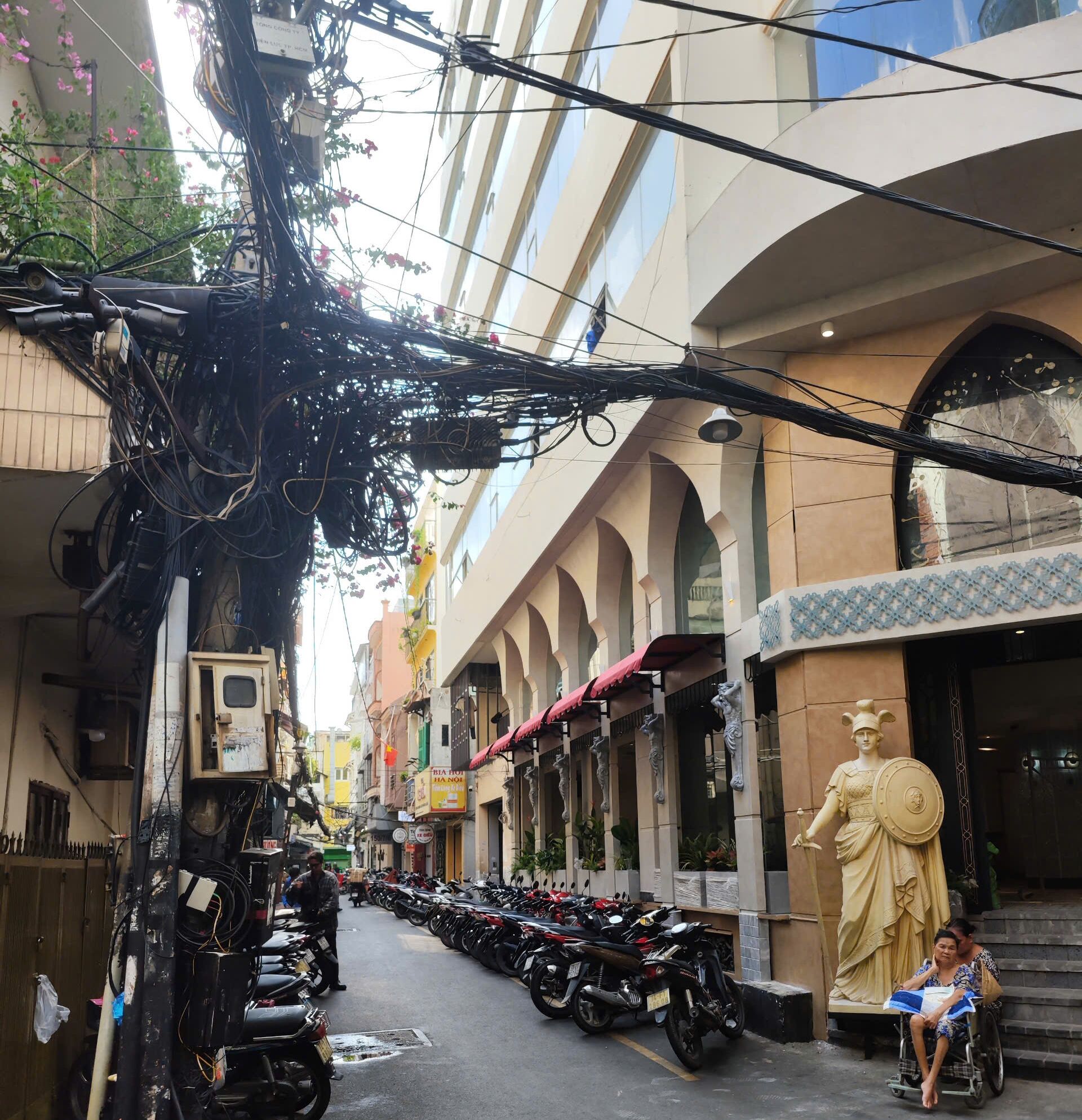 A street with parked motorcycles, a statue, and a building with arches.