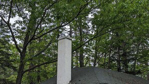 Una cabaña blanca de una sola planta con chimenea, puerta de madera y ventana.