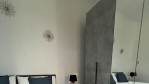 Une chambre moderne avec un grand lit, une table de chevet, un miroir et des œuvres d’art décoratives au mur.