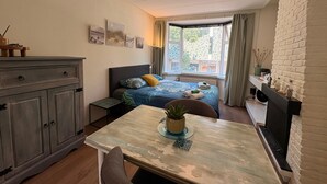 A bedroom with a bed, bedside table, and a window with curtains. - Stylish Lottus Room in Duplex Near Center & UMCG (Groningen)