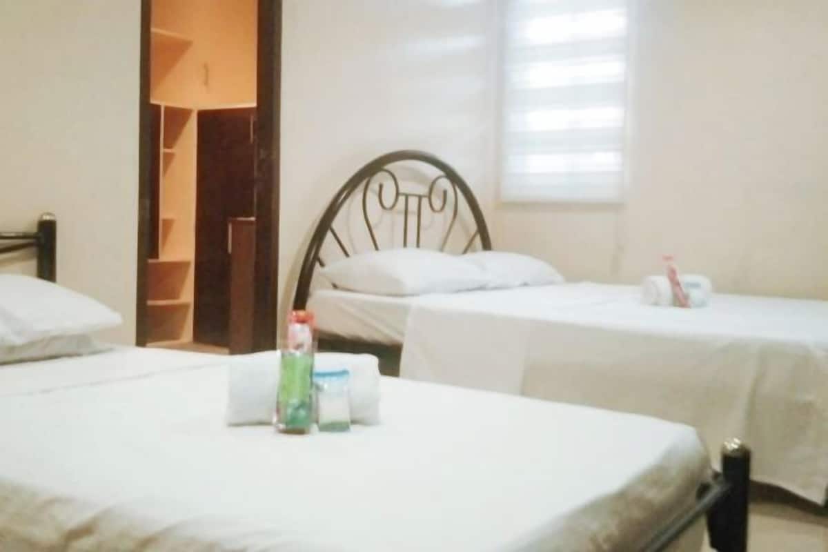 A hotel room with two beds, a wardrobe, and a window with blinds.