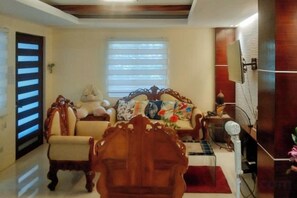 Una sala de estar con sofá, sillones, una mesa de centro de madera y televisor.