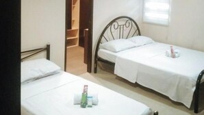 A room with two single beds, a wooden wardrobe, and a window with blinds.