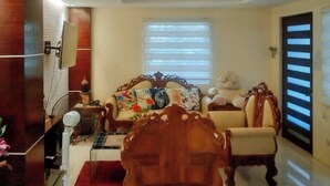 A living room with a sofa set, a wooden coffee table, and a television mounted on the wall.