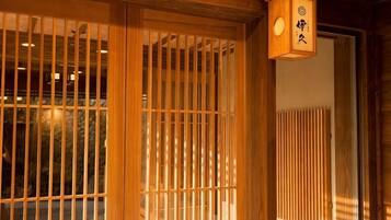 A traditional Japanese room with sliding doors, a wooden ceiling, and a hanging lantern.