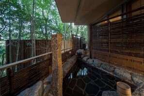 Une zone dallée de pierres, avec une rambarde en bois, un poteau en bois et un mur de pierres.