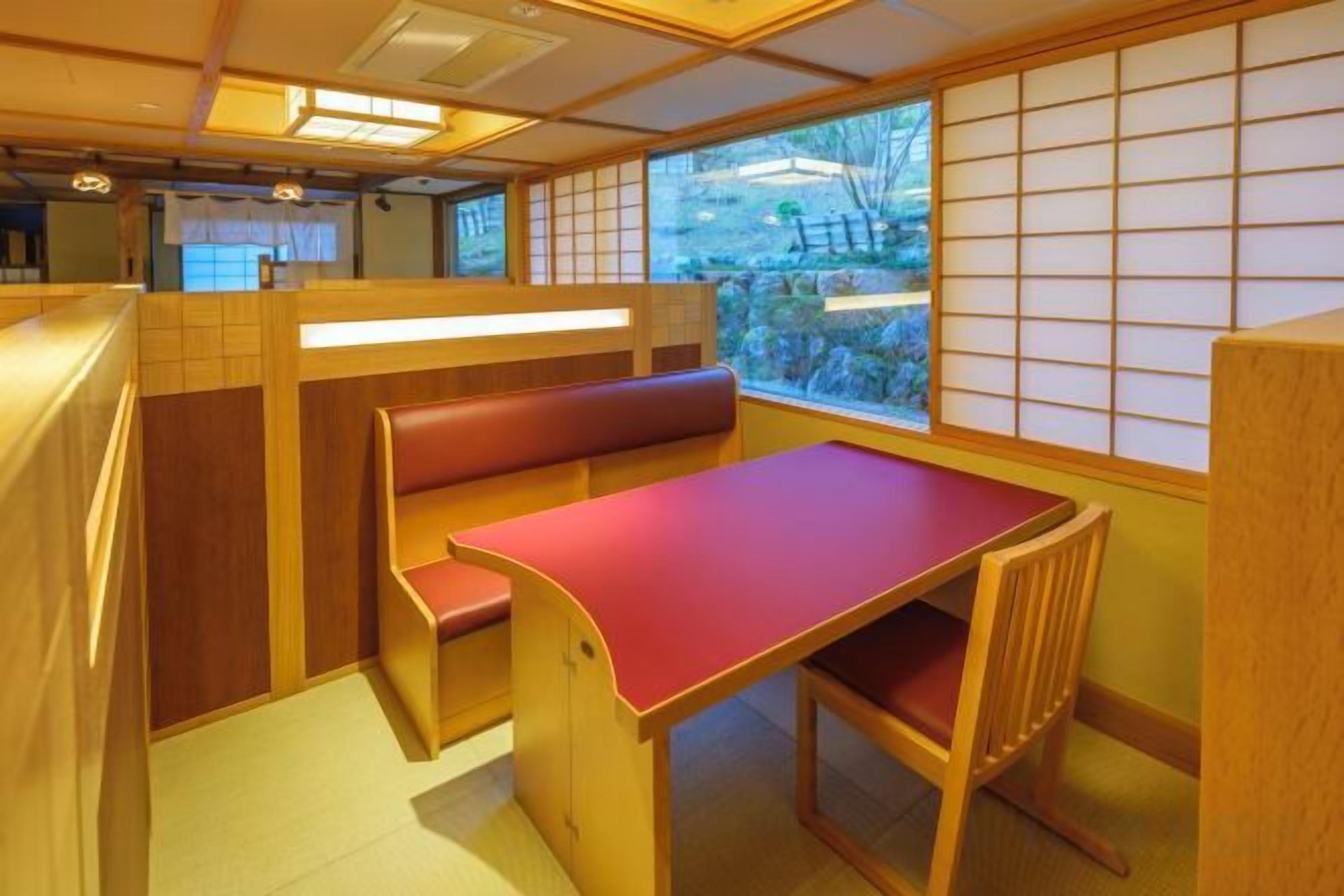 A traditional Japanese room with tatami flooring, a low wooden table, and a cushioned bench.