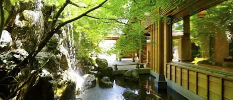A traditional Japanese garden with a koi pond, rocks, and a wooden walkway.