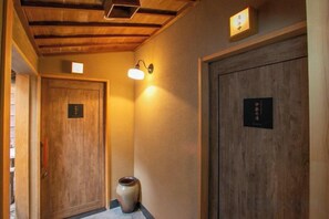 A hallway with wooden doors, a wall-mounted light fixture, and a decorative vase.
