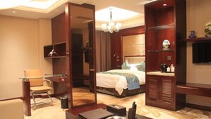 Una habitación de hotel con una cama, un escritorio de vidrio, una silla, un televisor y un espejo.