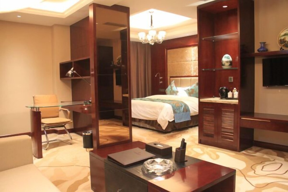 Une chambre d’hôtel comprenant un lit, un bureau en verre, une chaise, une télévision et un miroir.