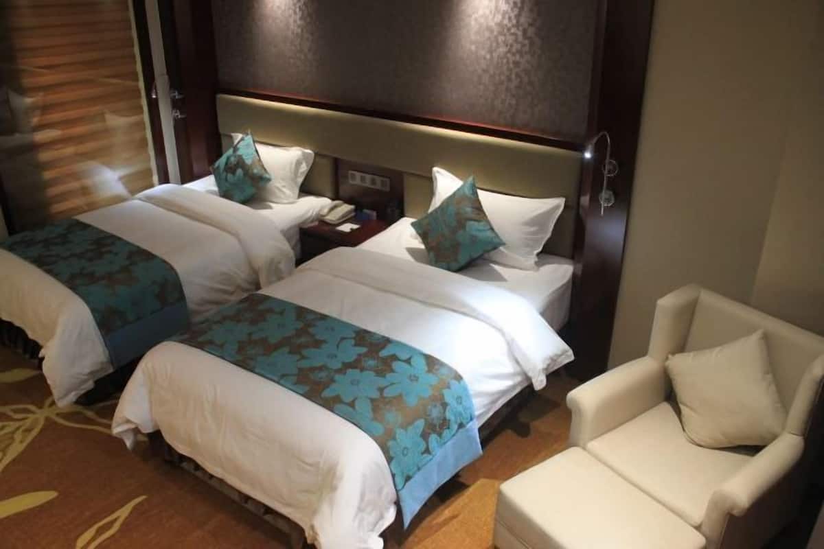A hotel room with two beds, a chair, and a nightstand with a phone.