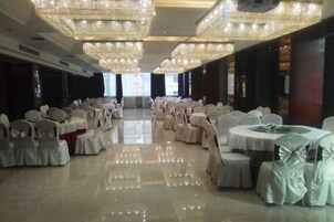 Un salón de banquetes con mesas y sillas redondas, candelabros y suelo pulido.