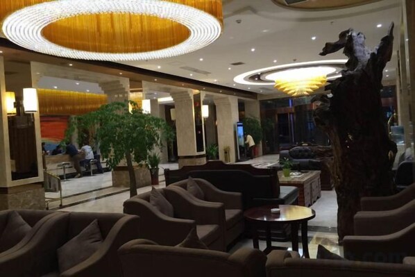 A hotel lobby with seating areas, a reception desk, and a large decorative sculpture.