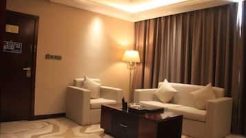A hotel room with a sofa set, a coffee table, a lamp, and a patterned carpet.
