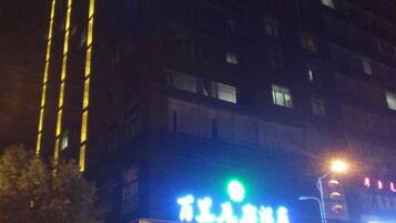 A building with illuminated signage, a streetlight, and a tree in the foreground.