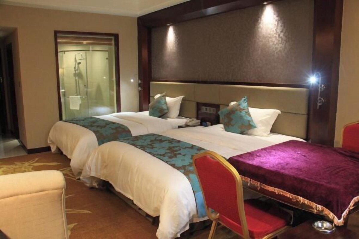 Habitación de hotel con dos camas, ducha y una silla roja.