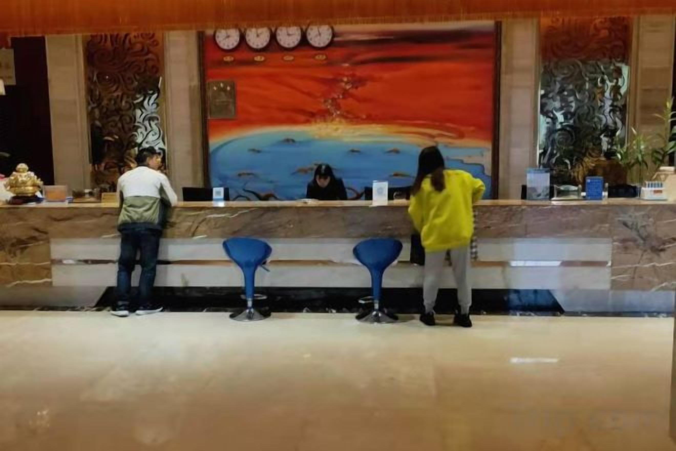 A reception area with a counter, blue bar stools, and a large painting on the wall.
