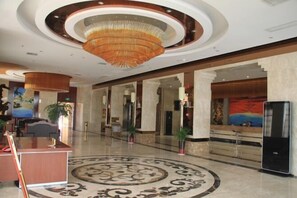 A spacious lobby with a large circular patterned carpet, a reception desk, and a modern chandelier. - Barry Gallery along the River hotel (Yanhe)