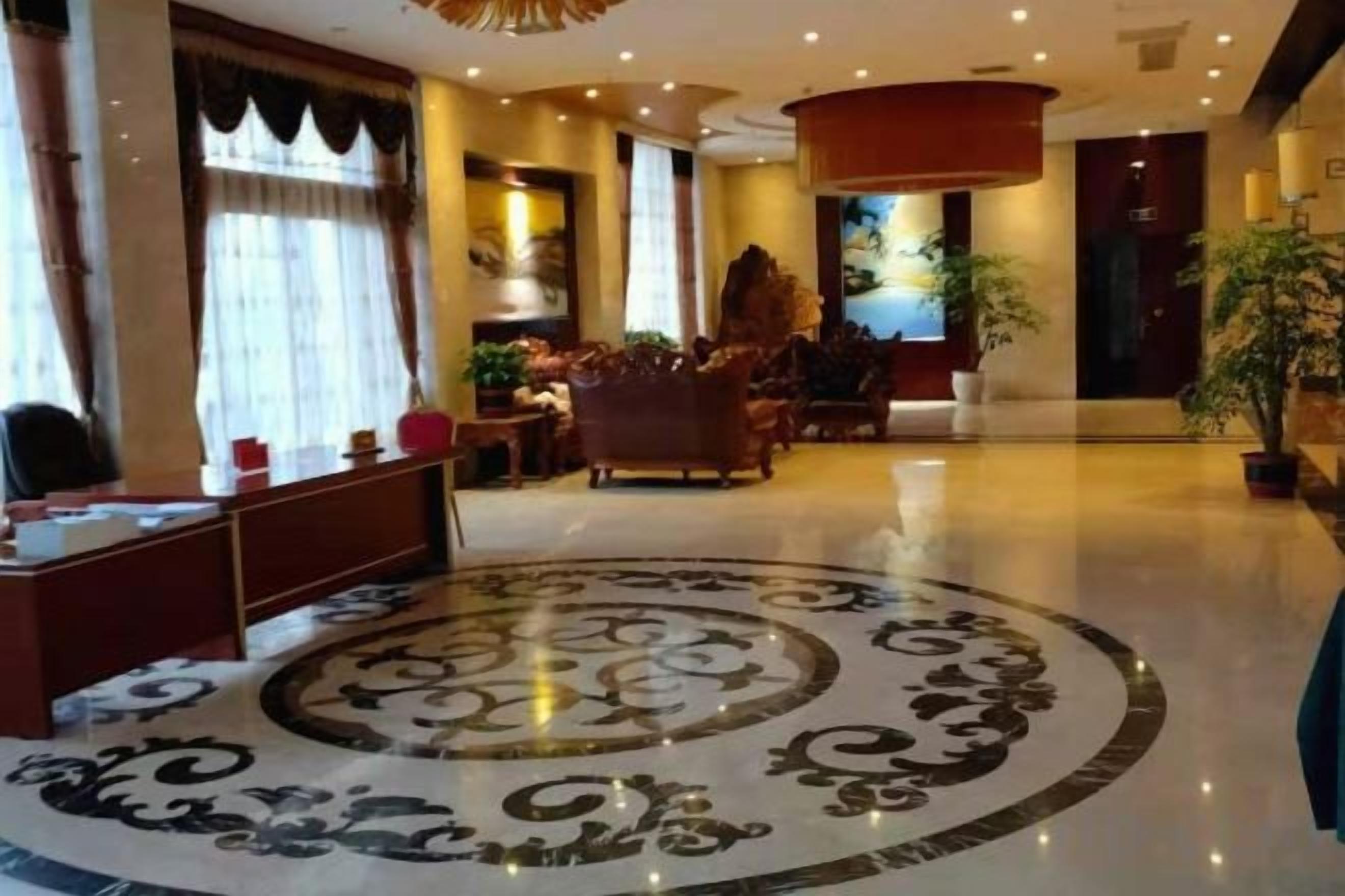 A hotel lobby with a reception desk, seating area, and a decorative floor pattern.