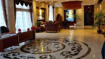 A hotel lobby with a reception desk, seating area, and a decorative floor pattern.