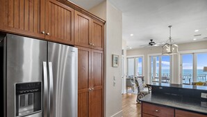 Eine Küche mit Holzschränken, einem Edelstahlkühlschrank und einer großen Kochinsel mit schwarzer Arbeitsplatte.