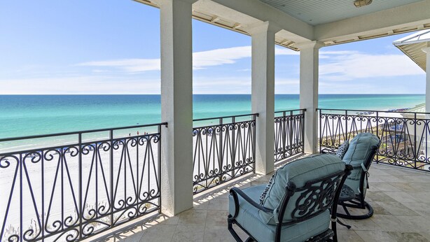 Ein überdachter Balkon mit zwei Schaukelstühlen und Blick auf das Meer, mit weißer Decke.
