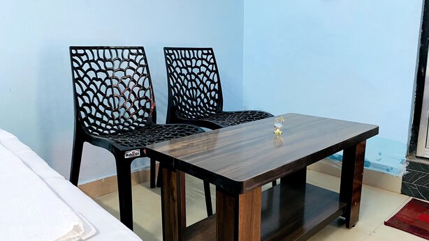 A small dining area with two black chairs and a wooden table. - Hanumat Home Stay (Faizabad)