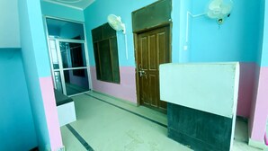 A hallway with a blue and pink wall, a wooden door, and a white cabinet. - Hanumat Home Stay (Faizabad)