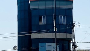 A multi-story building with a flat roof and a signboard advertising a 24-hour service. - Hanumat Home Stay (Faizabad)