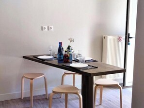 A dining area with a table set for two, two stools, and a radiator in the background. - Joanna Deluxe Apartments One-Bedroom Apartment (Kynopiastai)