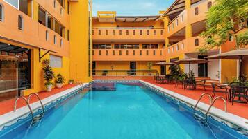 Una piscina con plataforma roja, rodeada por edificios amarillos con múltiples balcones y zonas de estar al aire libre.