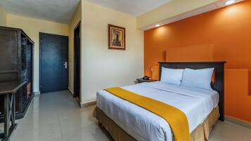 A hotel room with a bed, a nightstand, a desk, and a door.