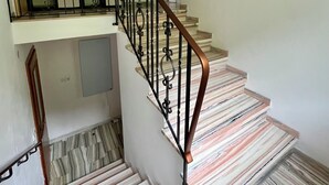 A staircase with a metal railing and patterned floor tiles.